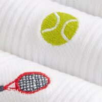 close up photo of a tennis racket and ball on a pair of white socks