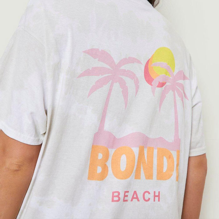 Custom screen-printed Bondi Beach design on an AS Colour white t-shirt with pastel palm trees and a sunset graphic