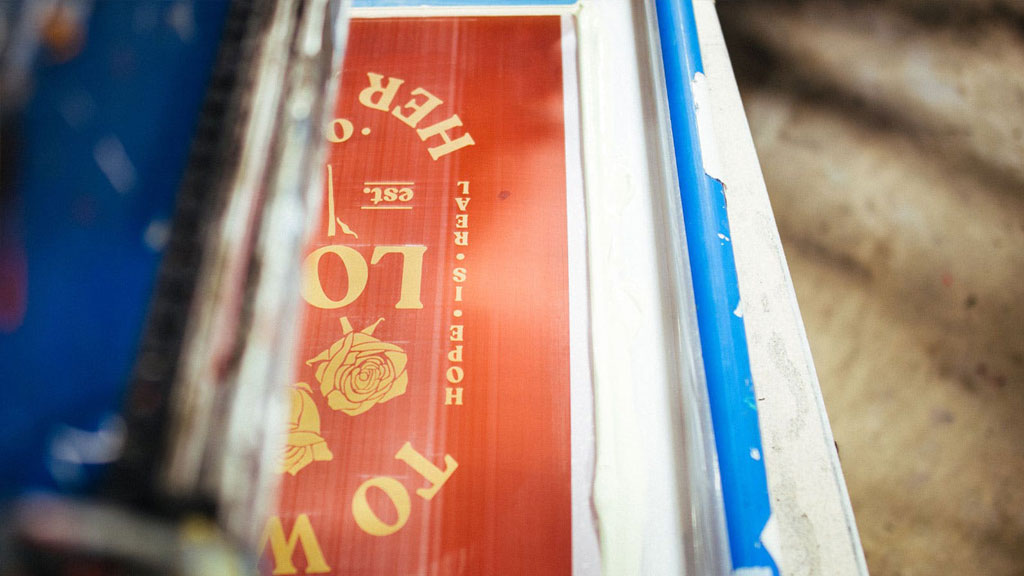 A vibrant screen printing design in progress, showcasing the message 'HOPE IS REAL' with artistic rose details.