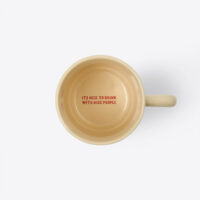 A top-down view looking into a sand beige ceramic stacking coffee mug, showing custom red text printed on the inside bottom that reads "ITS NICE TO DRINK WITH NICE PEOPLE".
