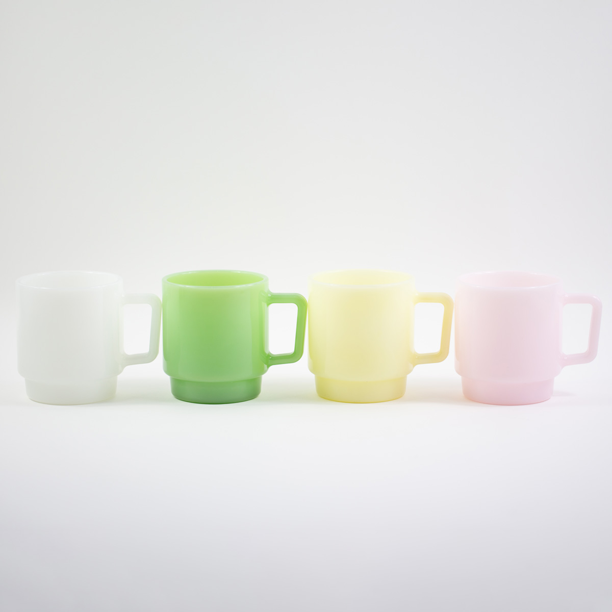Collection of custom milk glass mugs in white, jade green, yellow, and soft pink