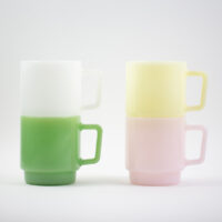 Two stacks of colourful retro milk glass mugs showing space-saving stackable design